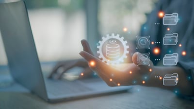 a person using a computer, with icons overlaid representing data management: interconnected folders and gears.