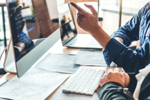 two people pointing to data on a computer