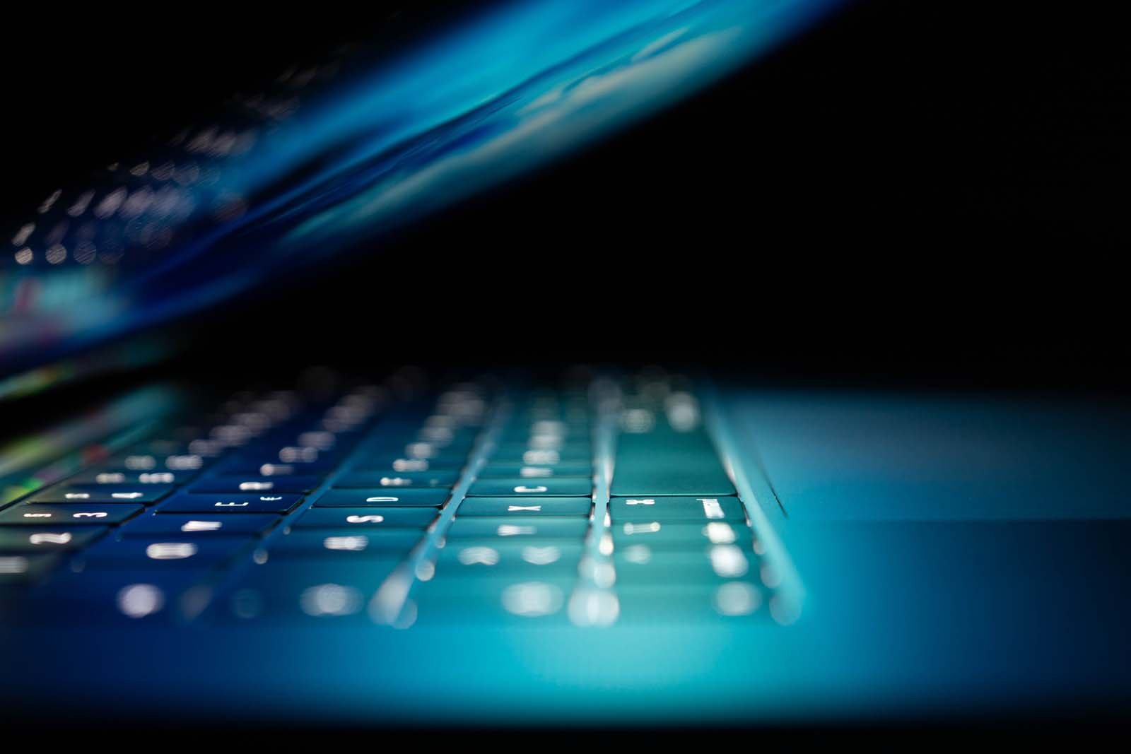 Side view of a keyboard with monitor reflecting off it.