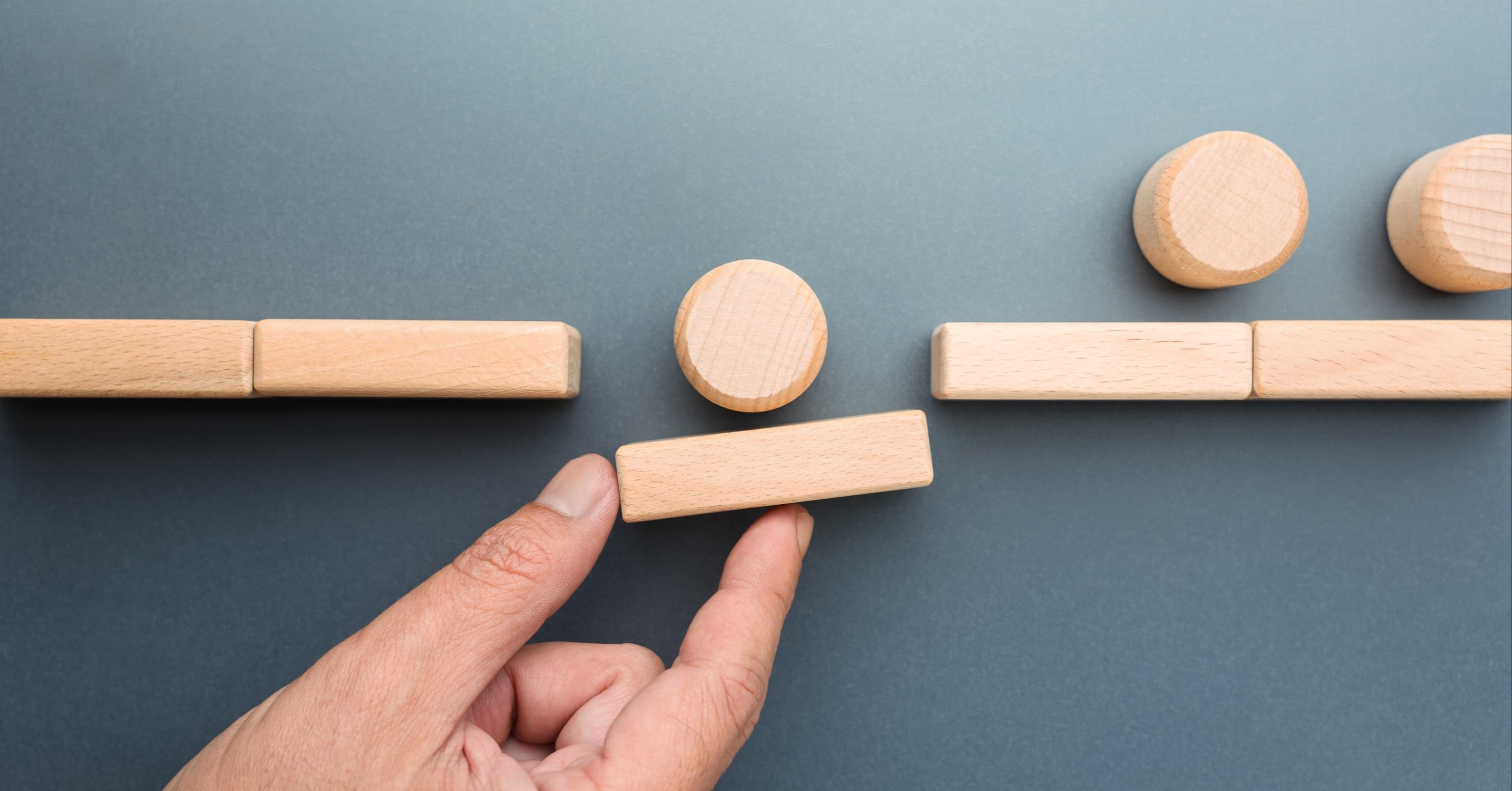 person holding a wooden section as a ball rolls over it, representing bridging a gap